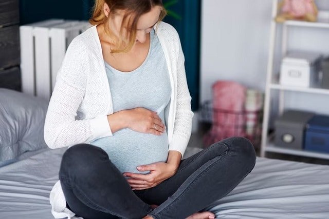 Femme-enceinte-assis-sur-lit