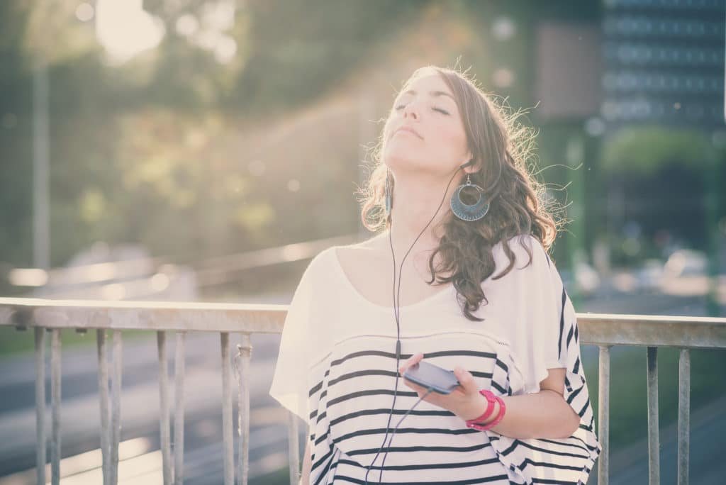 young beautiful brunette woman with smart phone listening music  in the city